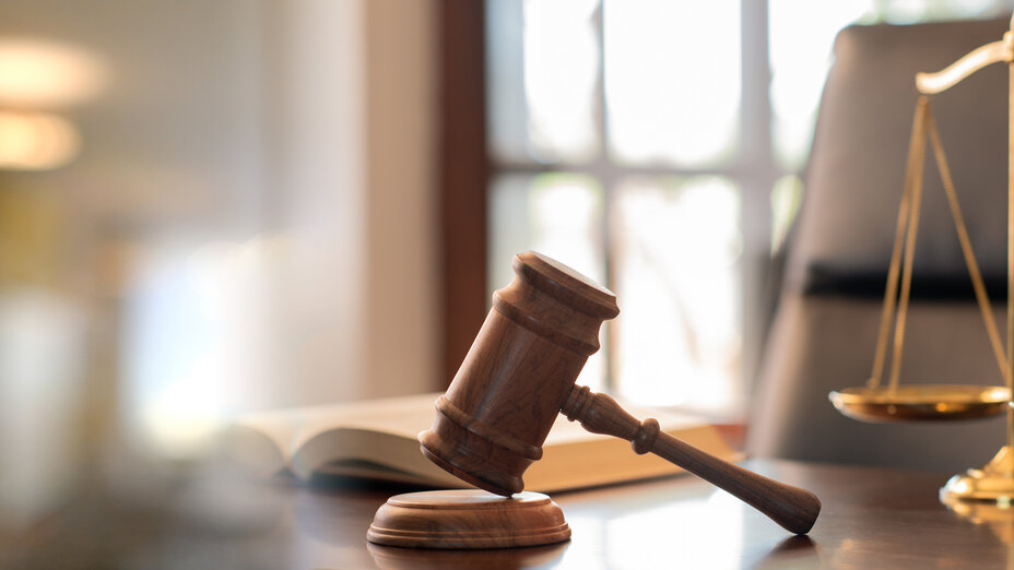 Richterhammer, Gesetzesbücher und Gerechtigkeitswaagen auf dem Schreibtisch in der Anwaltskanzlei