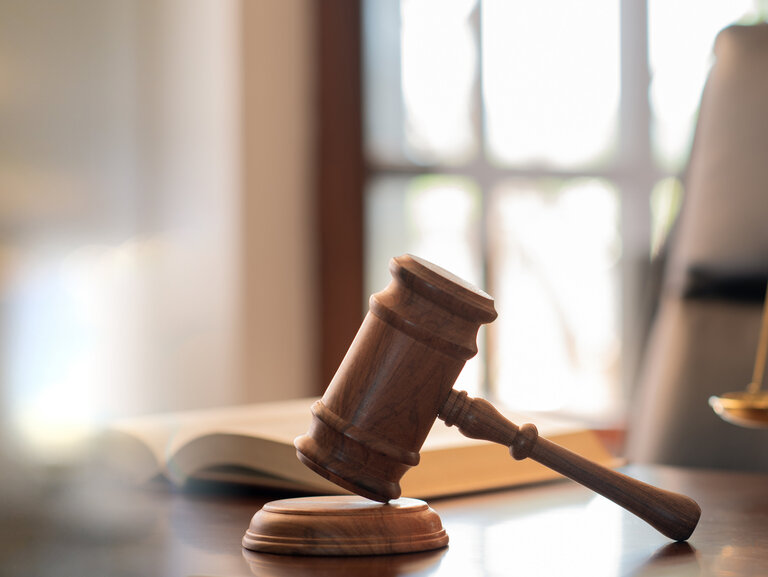 Richterhammer, Gesetzesbücher und Gerechtigkeitswaagen auf dem Schreibtisch in der Anwaltskanzlei